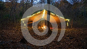 Primitive Tarp Shelter with campfire and fairy lights. Survival Bushcraft setup in the Blue Ridge Mountains near Asheville. During