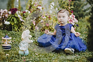 Princess amazed baby girl sitting on the grass with her toys