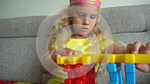 Princess girl with crown playing with colorful parts on sofa. Gimbal movement