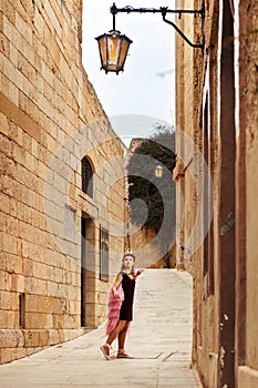 The princess girl is lost in the old streets of the castle town of yellow stone looking at the old-fashioned lantern