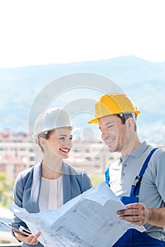 Principal and builder reading blueprints on construction site photo