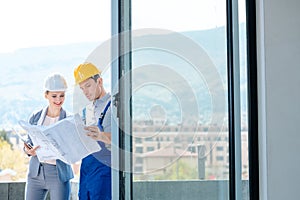 Principal and builder reading blueprints on construction site photo
