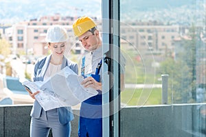 Principal and builder reading blueprints on construction site photo