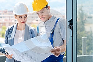 Principal and builder reading blueprints on construction site photo
