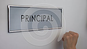 Principal office door, hand knocking closeup, visit to college chief, education
