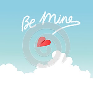 Heart shaped paper airplane flying over fluffy clouds and skywriting Be Mine. photo