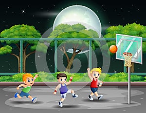 Happy boys playing basketball at the court in night