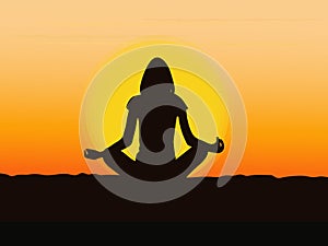 Silhouette of a young woman meditating yoga at sunrise or sunset