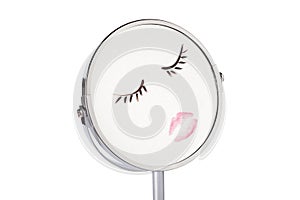 Print of lips and eyelashes on mirror maked by red lipstick and black mascara. Painted face drawing on facial mirror. Desktop make photo
