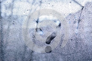 A print of a question mark on the wet window glass