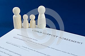 Printed child support agreement with man, woman and children wooden figures