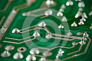 Printed circuit board green, electric, soldered legs of electrical components close-up macro view
