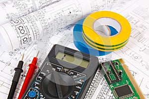 Printed drawings of electrical circuits, digital multimeter, electronic board and insulating tape.