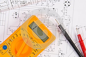 Printed drawings of electrical circuits and digital multimeter. Science, technology and electronics.