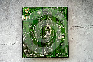 Printed green circuit board with electrical shot isolated on concrete background
