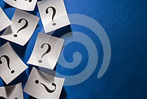 Printed question marks on white cards over blue