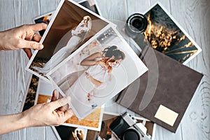 Printed wedding photos with the bride and groom, a vintage black camera, photoalbum and woman hands with two photos