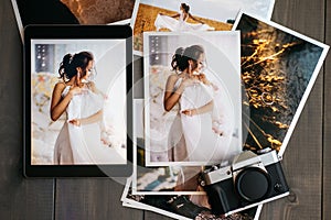 Printed wedding photos with the bride, a vintage black camera and a black tablet with a picture of bride