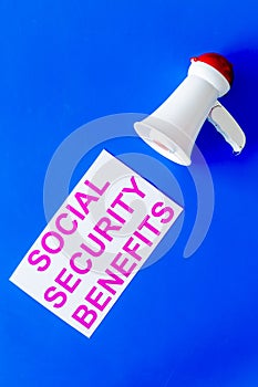 Printed words social security benefits near megaphone on blue with computer keyboard top view space for text