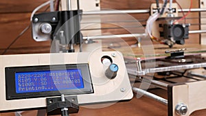 The printer prints the gear. The display shows information about nozzle movements and temperature.