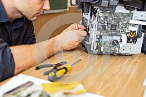 printer repair technician. A male handyman inspects a printer before starting repairs in a client's apartment.