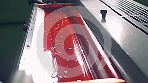 Printing roller is rotating and dipping itself into red paint