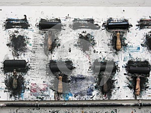 Printmaking rollers hanging on an art studio wall in the messy workshop