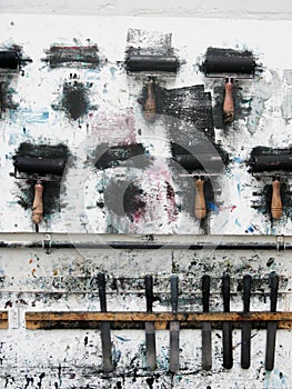 Printmaking rollers hanging on an art studio wall in the messy workshop