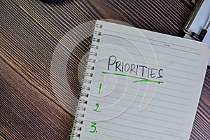 Priorities write on a book isolated on Wooden Table