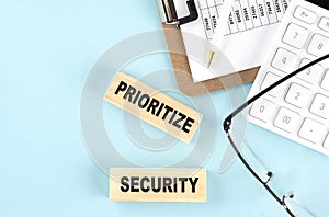 PRIORITIZE SECURITY text written on wooden block with clipboard,eye glasses and calculator Business concept