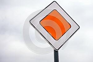 Priority road sign against cloudy sky