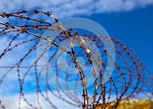 Prison. Barbed wire. Barbed wire on blue sky background with white clouds. Wire boom. Military conflict . Syria.