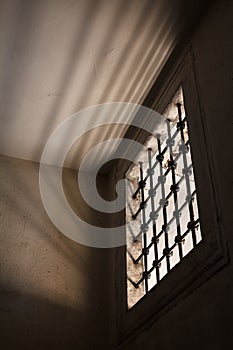 Prison cell with light shining through a barred window