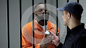 Prison guard giving afro-american imprisoned male dose of drugs illegal activity
