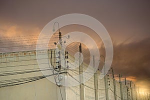 Prison security electric fence and high concrete wall. Prison high voltage fence. Barbed wire security fence. Razor wire jail