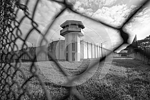 Prison watchtower protected by wire of prison fence.White prison wall and guard tower with coiled barbed wire.Criminal justice