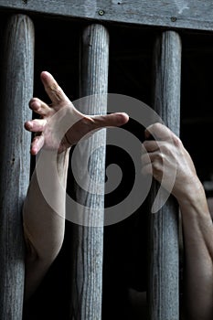 Prisoner behind wooden bars begging for help