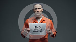 Prisoner holding End inhuman conditions sign in cell, human rights protection