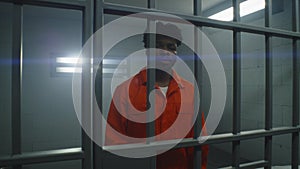 Prisoner stands behind prison cell bars