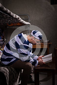Prisoner wearing prison uniform reading a book or a bible while