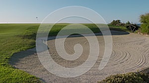 Pristine Golf Course Bunker with Raked Sand Patterns under Clear Skies