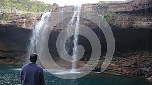 Pristine natural waterfall falling streams and man enjoying at morning from flat angle