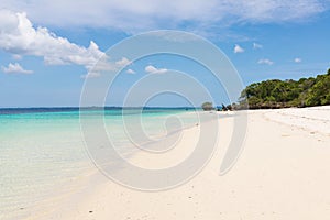 Pristine white tropical beach with blue sea and lush vegetation