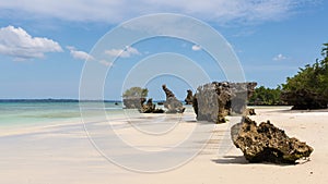 Pristine white tropical beach with rocks, blue sea and lush vegetation on the African Island of Misali, Pemba, Zanzibar. photo