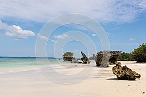 Pristine white tropical beach with rocks, blue sea and lush vegetation on the African Island of Misali, Pemba, Zanzibar.