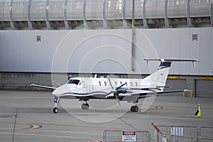 Private 2-prop plane parked next to an airport wall