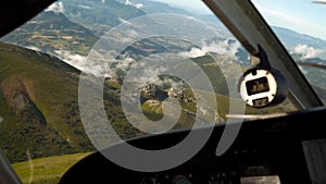 Private aircraft makes a turn, cabin view. Flying high above mountains, clouds