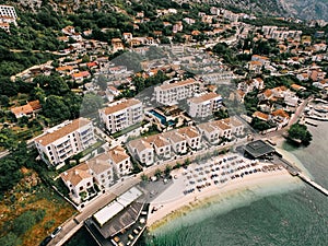 Private beach with sun umbrellas near the Huma Kotor Bay Hotel. Dobrota, Montenegro. Drone