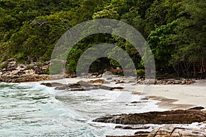 Private beach surrounded by tropical forest and coastal cliffs on the island