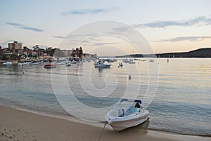 Private boat on the beach at Manly Cove during pink sunset in Sydney